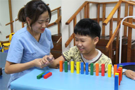 치료사와 아동이 도미노 블록을 쌓고 있는 모습